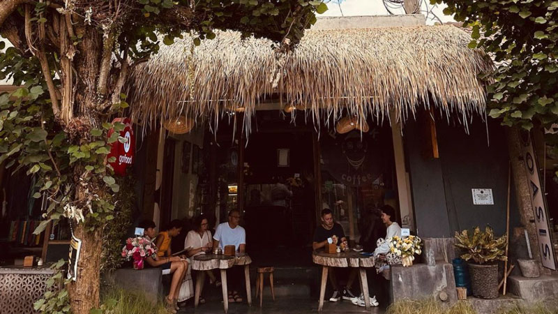 Relaxed atmosphere in front of Freak Coffee Ubud with a thatched roof.