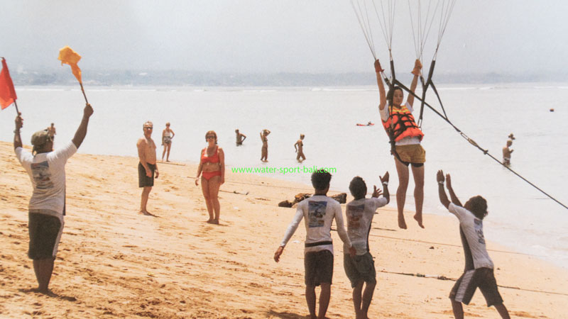 Parasailing landing on Sanur Beach with assistance from the ground crew in Bali