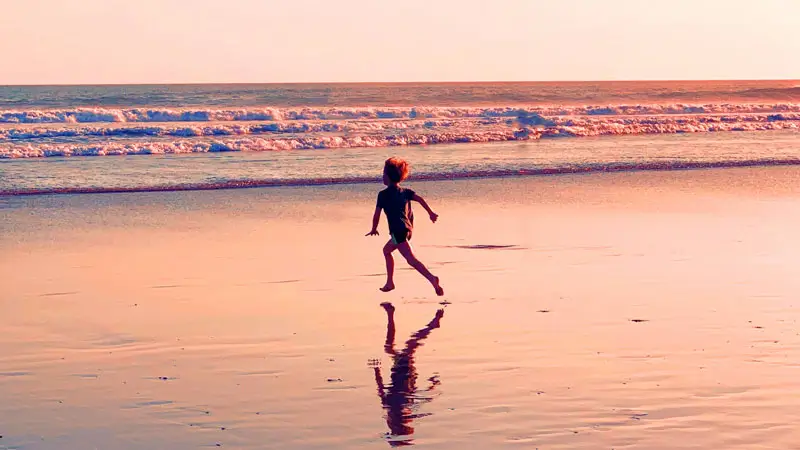 Child playing on the beach at sunset in Bali, reflecting the peaceful low season atmosphere.