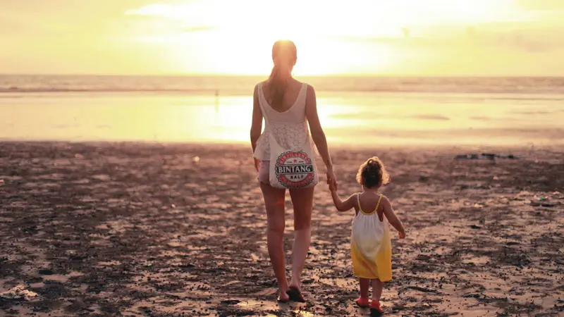 Mother and daughter walking on the beach at sunset in Bali