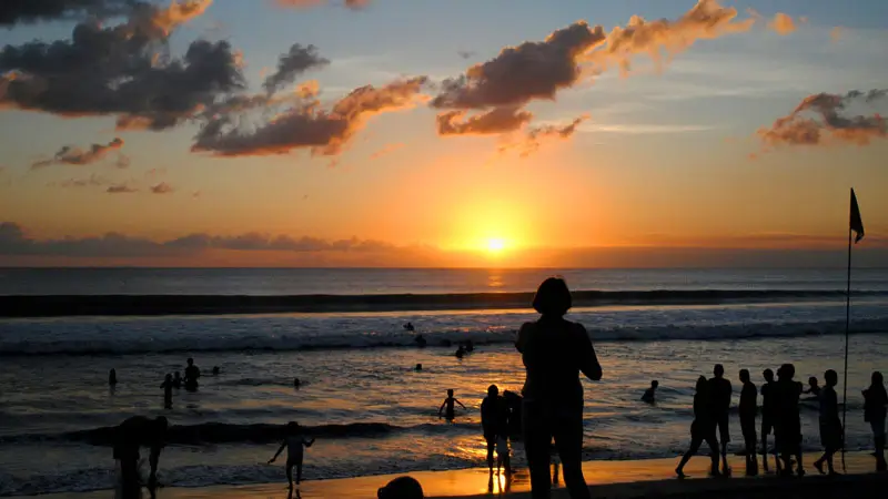 Tourists enjoy the sunset at the shoreline