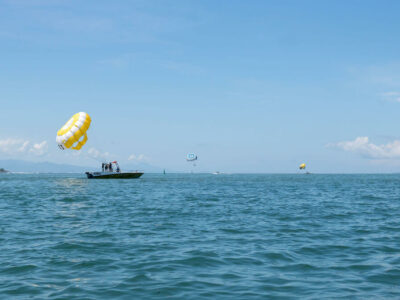 Parasailing adventure in Bali with a beach view as a backdrop, part of 5 Things You Need to Know About Bali Parasailing.