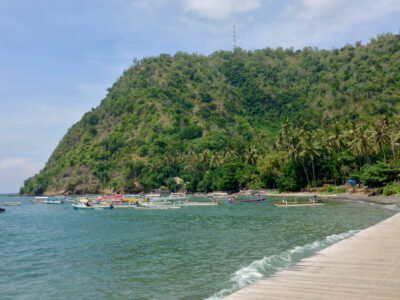 Scenic view of Labuhan Amuk Beach with traditional boats and lush greenery in Karangasem, Bali