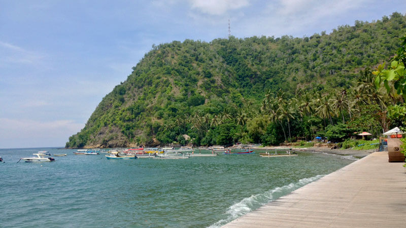 Scenic view of Labuhan Amuk Beach with traditional boats and lush greenery in Karangasem, Bali