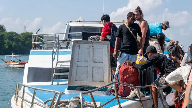 Passengers boarding a speedboat with their luggage in Bali