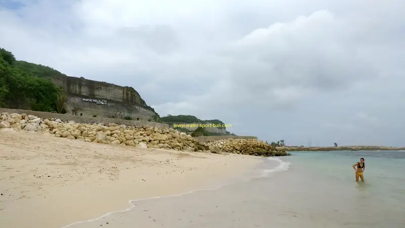 Tourists swim on the beach with a backdrop of limestone cliffs