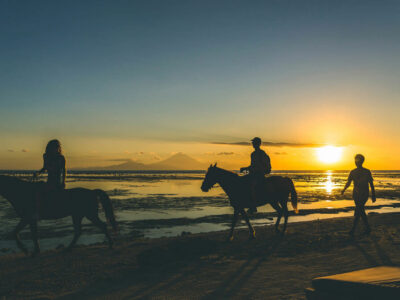 Horseback riding on Gili Trawangan beach at sunset with Mount Agung in the distance.