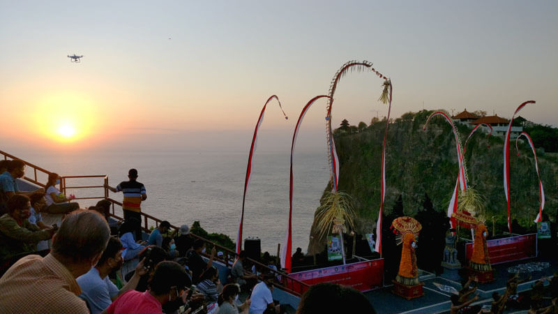 Kecak dance performance at sunset at Uluwatu Temple with audience and ocean backdrop