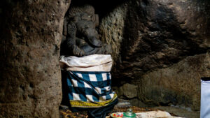 Statue of Lord Ganesha draped in a traditional checkered cloth in the Goa Gajah Temple cave