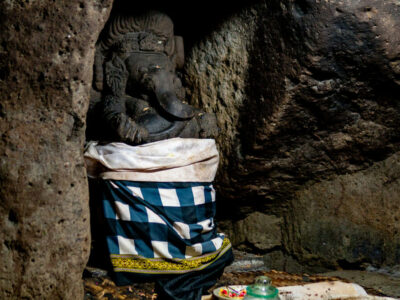 Statue of Lord Ganesha draped in a traditional checkered cloth in the Goa Gajah Temple cave