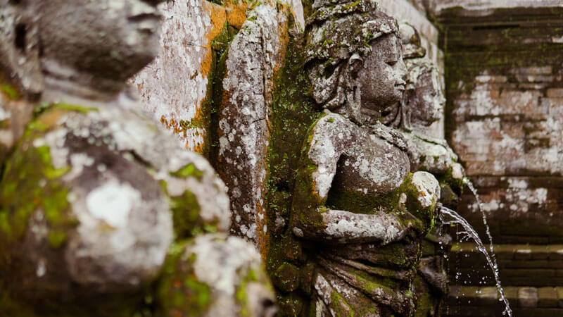 Detailed carving of a deity on the bathing pool wall at Elephant Cave Temple Bali