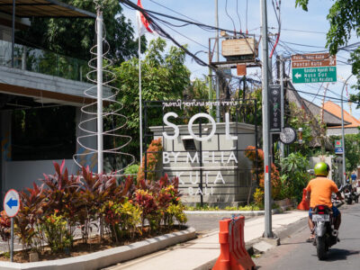 Busy Bali street with directional signage to Kuta Beach, showcasing typical transportation flow.