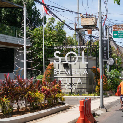 Busy Bali street with directional signage to Kuta Beach, showcasing typical transportation flow.