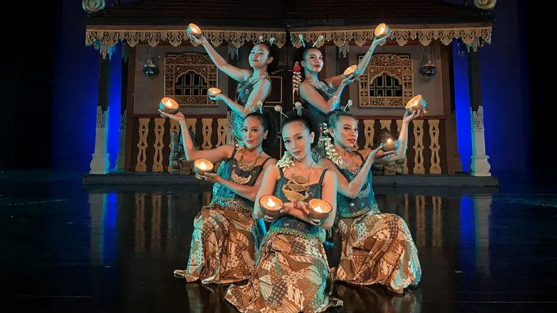 Performers presenting a traditional Javanese candle dance with intricate choreography and glowing candles. Image Credit: © Devdan