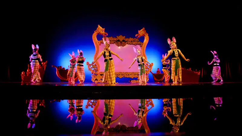 Devdan Show Bali performers in a traditional Javanese Wayang dance with colorful costumes and a vibrant stage backdrop. Image Credit: © Devdan