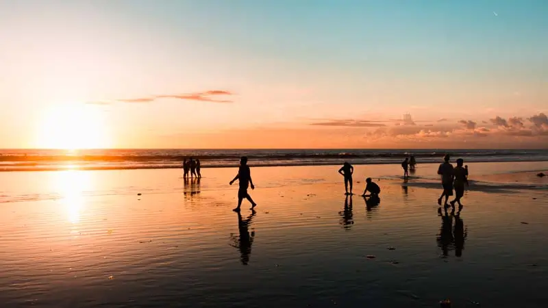 People walking on Kuta Beach at sunset, one of the best places to visit in Bali.