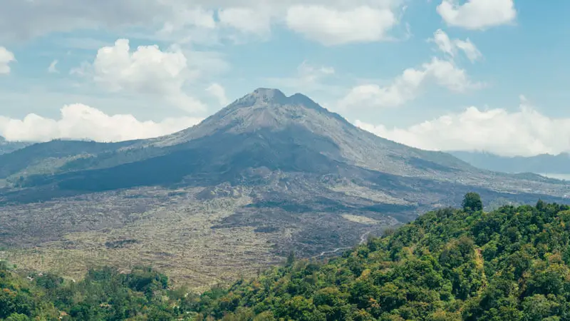 Mount Batur in Kintamani, Bali, with a scenic volcanic landscape and lush greenery.