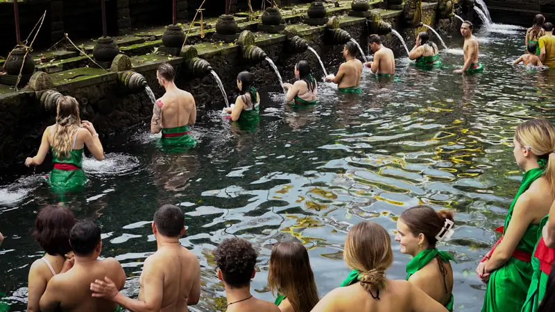 Tourists and locals performing the sacred Melukat purification ritual at Tirta Empul Temple in Bali’s holy spring waters.