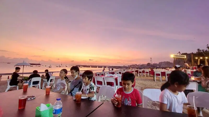 Beachfront dining at Jimbaran Beach, Bali, with a stunning sunset view and fresh seafood served on the sand.