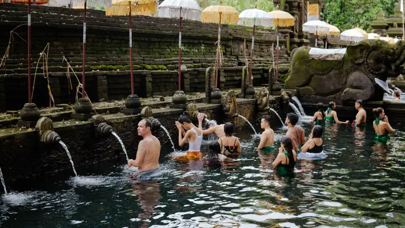 Tourists participate in a purification ritual at Tirta Empul Temple