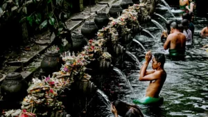 Tourists participating in a spiritual cleansing ritual at Tirta Empul Temple, a popular and budget-friendly attraction in Bali.