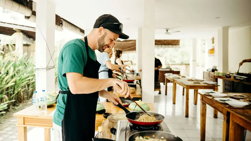 Participant cooking traditional Balinese dishes in an interactive cooking class in Sanur.