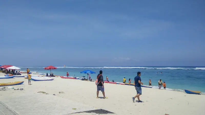 Visitors enjoying sunny Pandawa Beach Bali with clear ocean views and white sand.