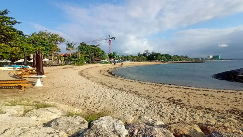 Wide view of Sanur Beach in Bali with golden sand and calm waters.