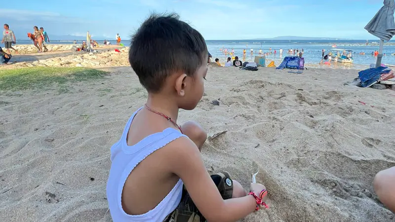 Child playing on the sandy shores of Sanur Beachfront.