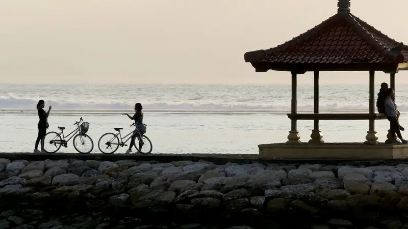 Cyclists and visitors near a gazebo during sunrise.