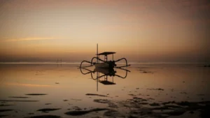 Sunrise at Sanur Beach Bali with a traditional jukung boat reflecting on the calm waters.