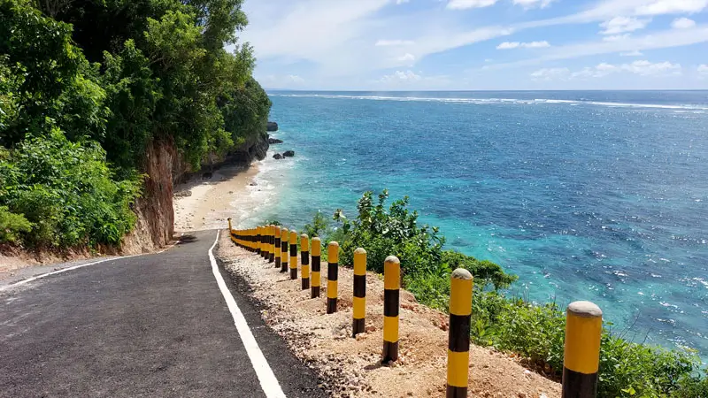 Scenic road leading to Tanah or Batu Barak Beach, surrounded by turquoise waters and coastal beauty.