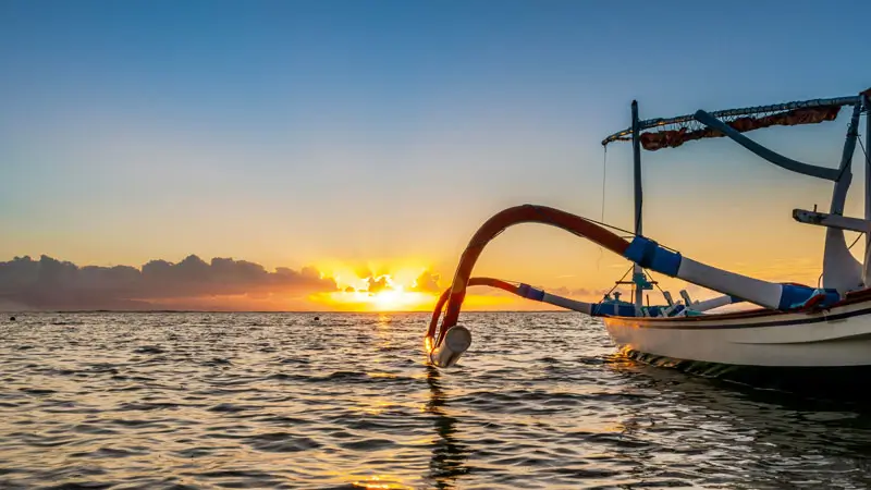 Traditional jukung boat in Sanur Beach at sunrise, showcasing Bali’s maritime heritage.