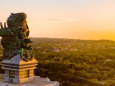 Aerial view of the Garuda Wisnu Kencana statue at sunset, overlooking lush green hills in Bali, Indonesia. © GWK Bali.